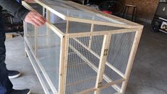 a man is standing next to a large bird cage in the garage with his hand on it