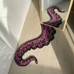 a pink and black octopus rug in front of a mirror with its reflection on the floor