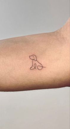 a small dog tattoo on the left forearm and arm, with a line drawing of a dog