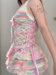 a woman wearing a dress made out of crochet and pink ribbon with tattoos on her arm