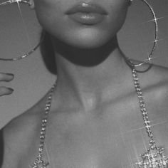 black and white photo of woman wearing large hoop earrings with crystal beads on her neck