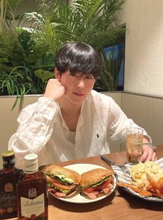 a man sitting at a table with two plates of food and drinks in front of him