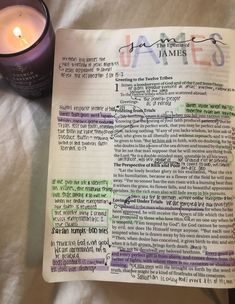 an open bible next to a candle on top of a white sheet with writing in it