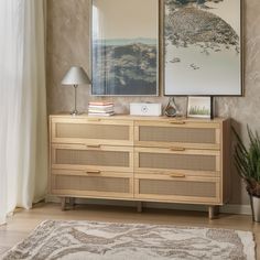 a wooden dresser sitting next to a window with pictures hanging on it's side