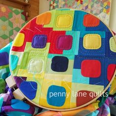 a colorful patchwork purse sitting on top of a pile of fabric