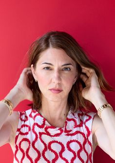 a woman in a red and white top holding her hair