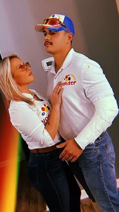 a man and woman are posing for a photo together in front of a rainbow background