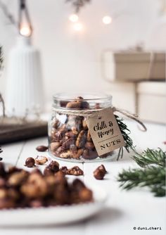 a jar filled with nuts sitting on top of a table next to a white plate