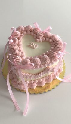 a heart - shaped cake with pink icing and ribbon on top is shown in front of a white background