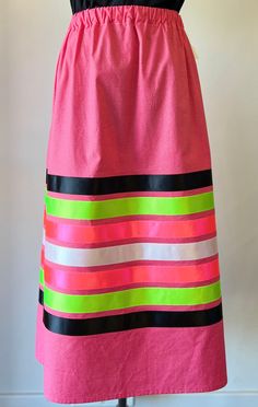 a pink and green striped apron on a mannequin