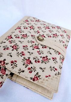 an open book with flowers on it sitting on a white table cloth covered in fabric