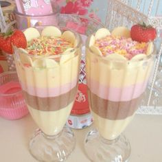 two desserts with strawberries and sprinkles in glasses on a table