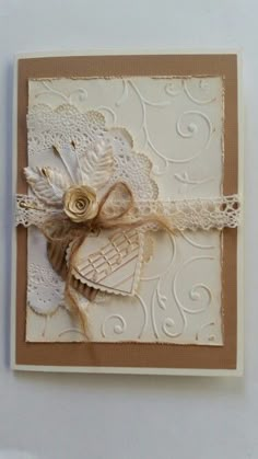 an ornate card with lace and flowers on the front is decorated in white, brown and beige