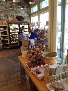 people are standing at the counter in a bakery with bread and pastries on it