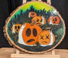 a wooden plaque with pumpkins painted on it's sides and faces in the center