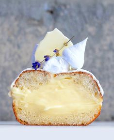 a piece of bread with cheese and blue flowers on top is sitting in front of a stone wall