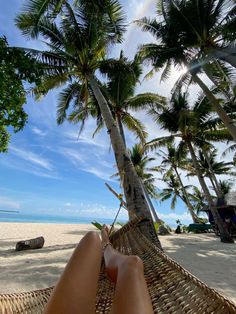 a person laying in a hammock on the beach with palm trees behind them