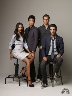 a group of people sitting next to each other in front of a white wall and chair