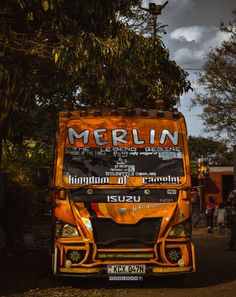 an orange and black truck parked next to a tree