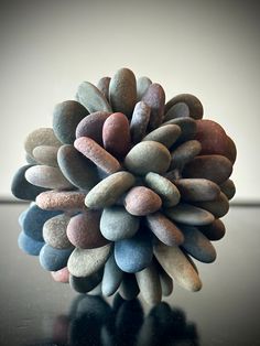 a close up of a pine cone shaped object on a black table with white walls in the background