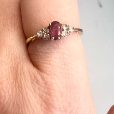 a woman's hand with a ring on it that has a pink stone in the middle