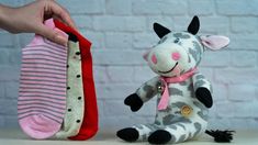 a stuffed cow sitting next to two pairs of sock socks and a hand holding one