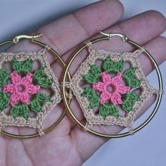 a pair of crocheted hoop earrings with pink and green flowers in the center