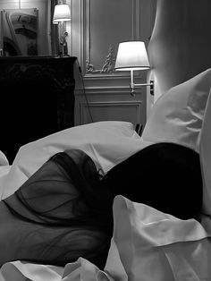 a black and white photo of a woman laying in bed with her head on the pillow