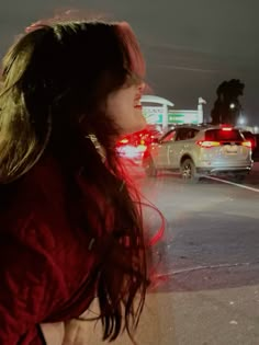 a woman is walking down the street at night with her hair blowing in the wind