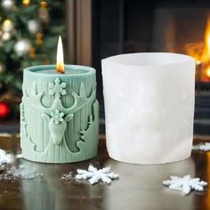 a lit candle sitting on top of a table next to a christmas tree and snowflakes