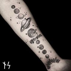 an arm tattoo with planets and stars on the outer half of it, in black ink