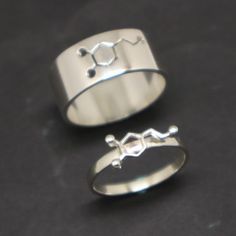 two silver rings sitting next to each other on top of a black surface with one ring in the middle