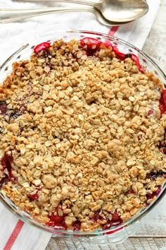 a pie with crumbled toppings in a glass dish next to a spoon