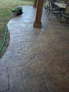 an outdoor patio with stone pavers and green hoses on the ground next to it