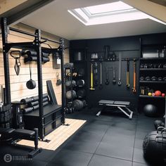 a home gym with black walls and lots of exercise equipment on the wall, along with an overhead skylight