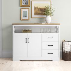 a white cabinet with wine glasses and pictures on the wall