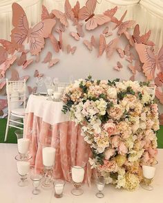 there is a table with flowers and candles on it, surrounded by pink butterfly decorations