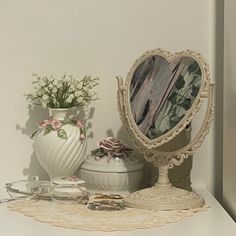 a white table topped with a mirror and vase filled with flowers