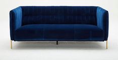 a blue velvet couch sitting on top of a white floor