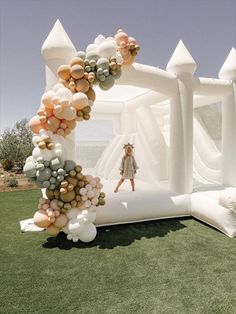 a woman standing in front of an arch made out of balloons