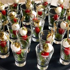 small glasses filled with food on top of a black table covered in condiments