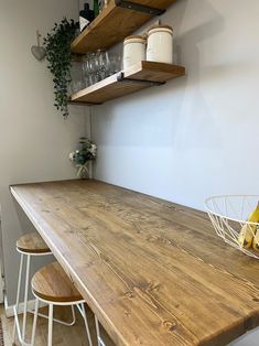 a wooden table topped with two white baskets filled with bananas and wine glasses sitting on top of it