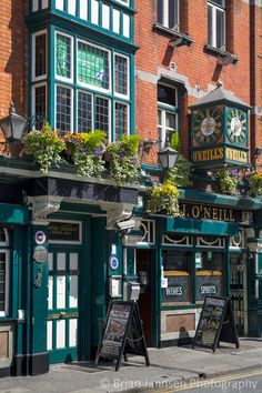 the outside of an irish pub with flowers on it's windows and signs in front