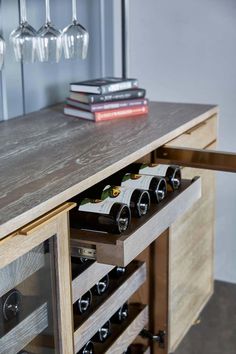 a wooden table with wine glasses and bottles on it next to a wall mounted wine glass rack