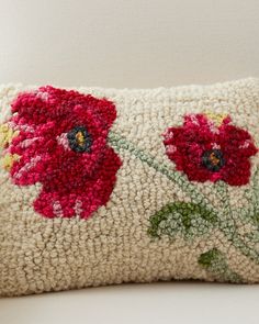 an embroidered pillow with red flowers on it