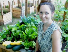 a woman sitting in front of a garden filled with vegetables