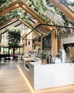 the inside of a restaurant with plants growing on the ceiling and tables in front of it