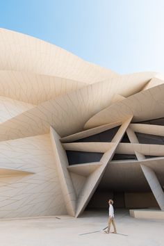 a woman is walking in front of a building that looks like a futuristic architectural structure