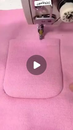 someone is using a sewing machine to sew on a pink cloth with the words hello kitty written in arabic