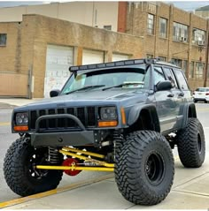 a gray jeep is parked on the side of the road in front of a building